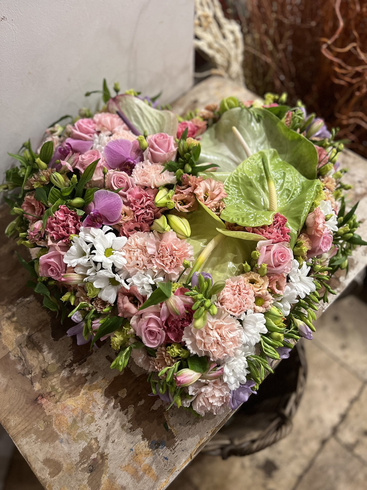 Coussin de deuil en forme de cœur, roses et orchidées roses avec anthuriums verts