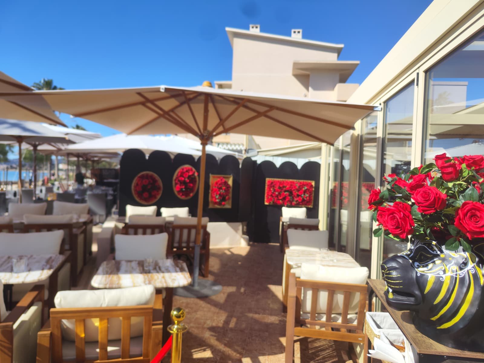Terrasse du restaurant Amore décorée de tableaux floraux rouges artificiels face à la mer