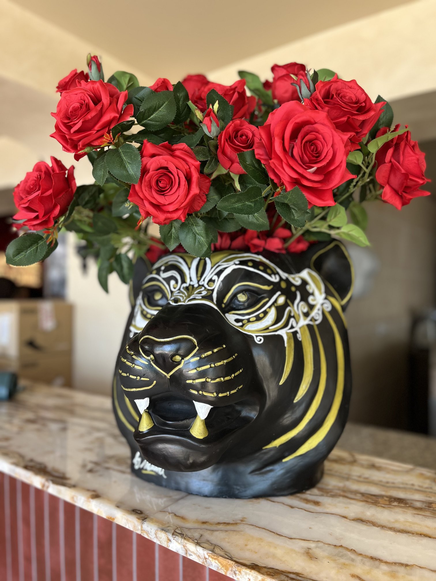 Bouquet de roses rouges artificielles dans un vase en forme de tête de tigre, restaurant Amore
