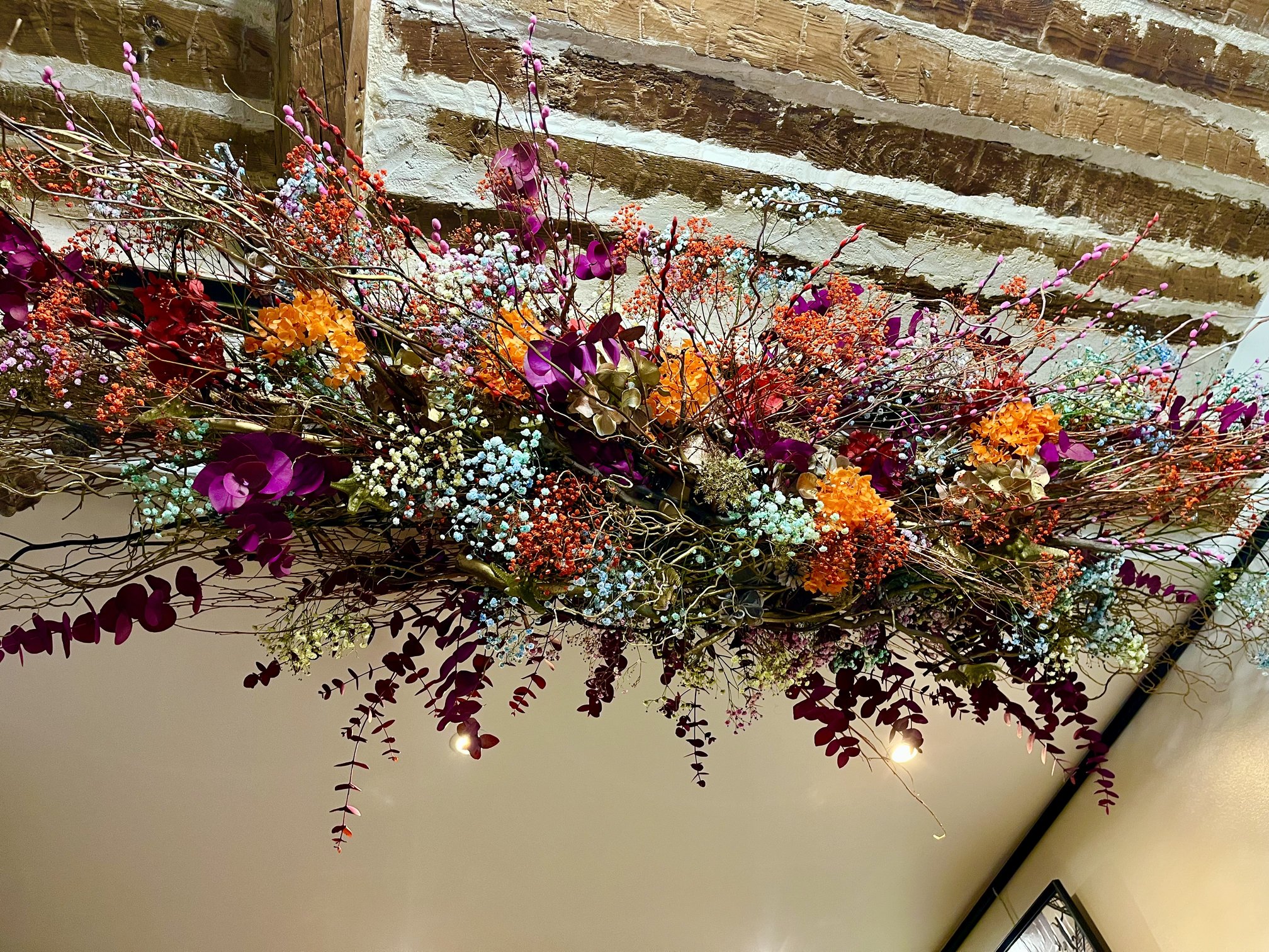 Composition suspendue de fleurs séchées roses et violettes au salon Le Confident Coiffeur