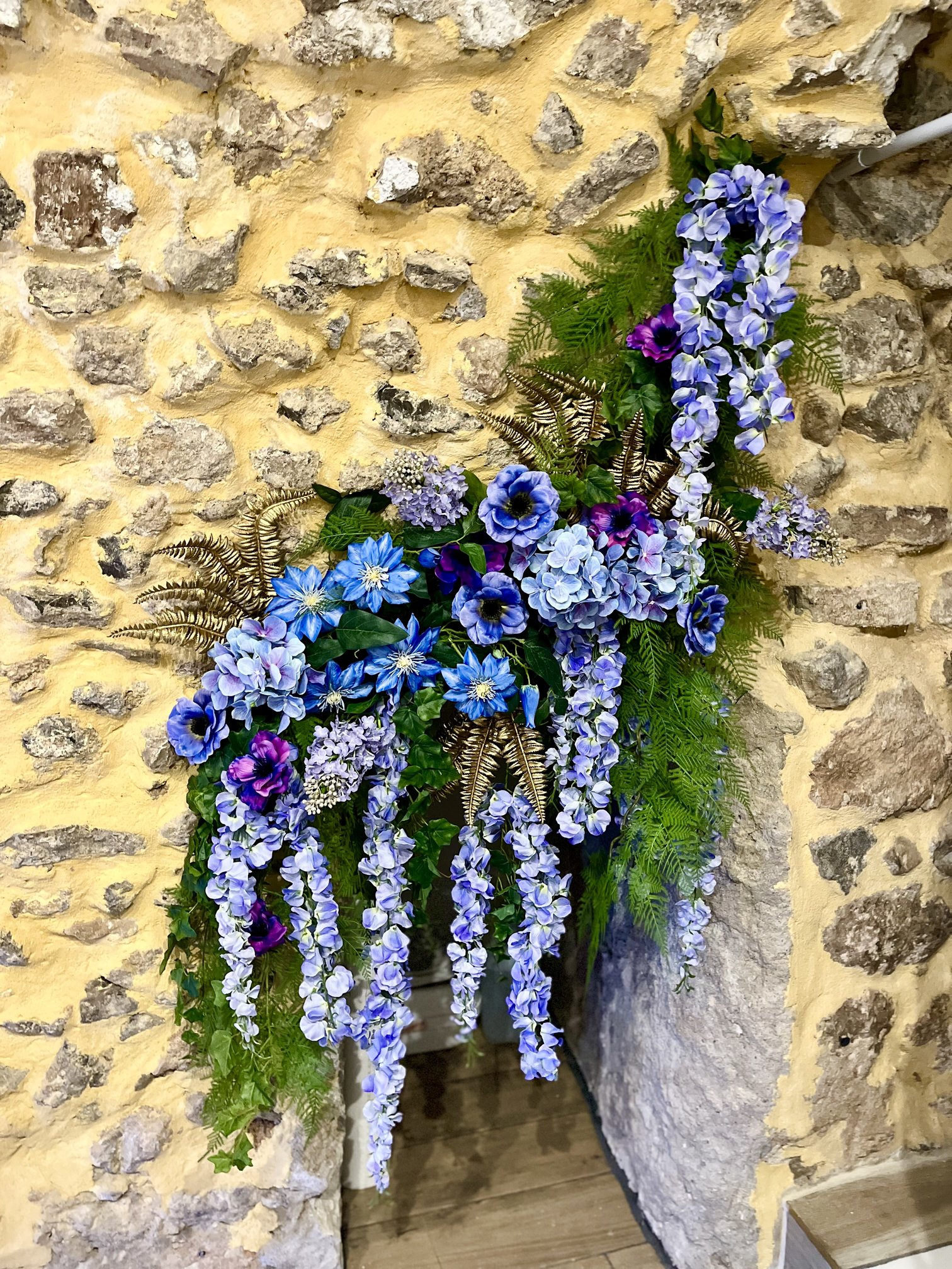 Décor floral artificiel bleu et violet sur la façade en pierre des Dames des Halles