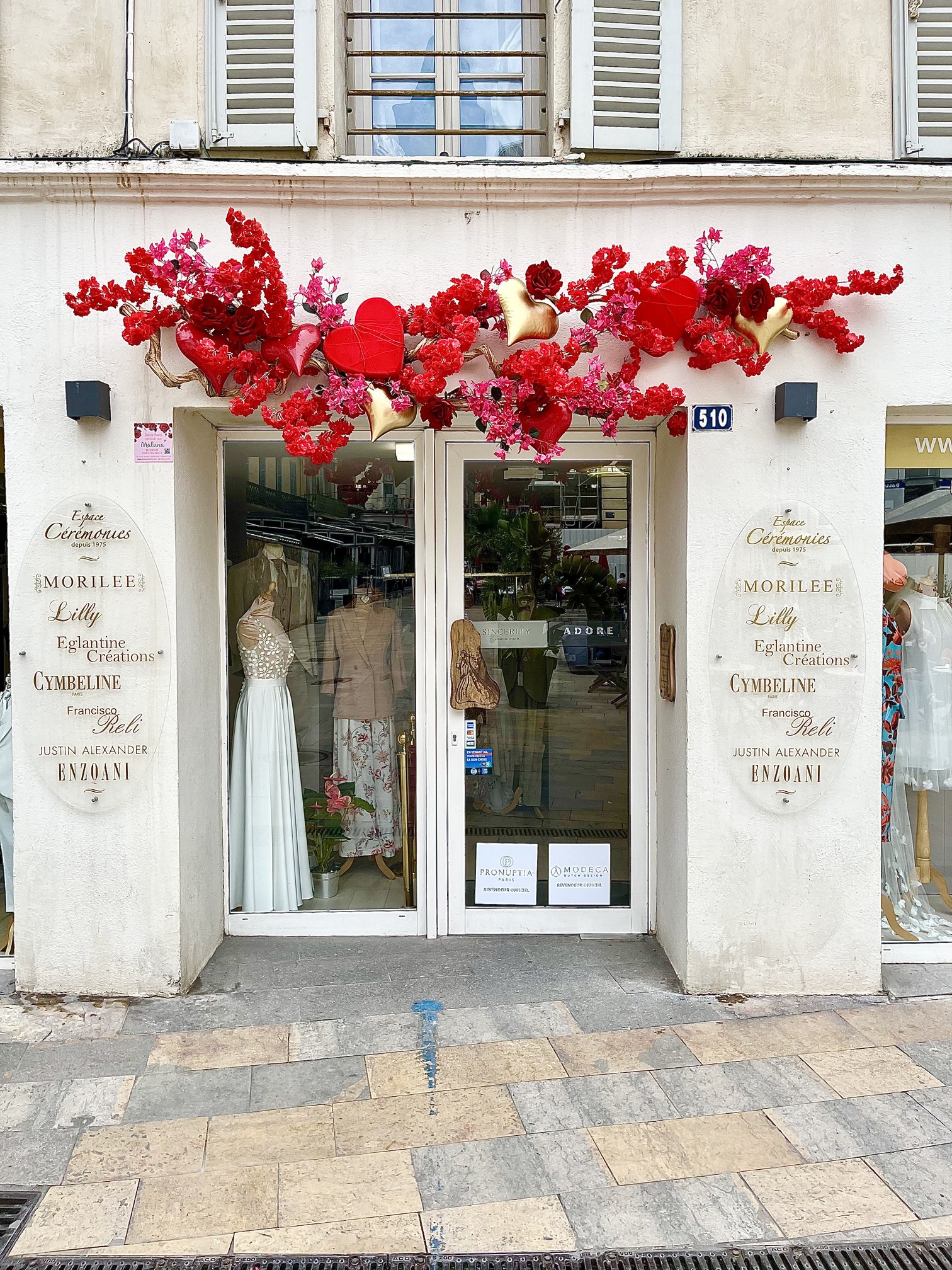 Façade de la boutique de robes de mariée Espace Cérémonies décorée de fleurs artificielles rouges