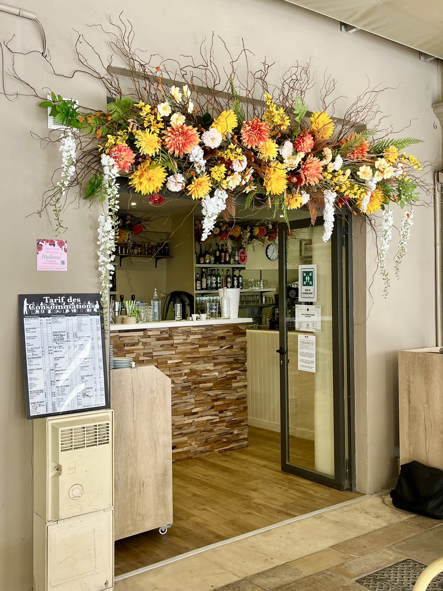 Devanture du restaurant Le Floréal ornée de fleurs artificielles jaunes et orange