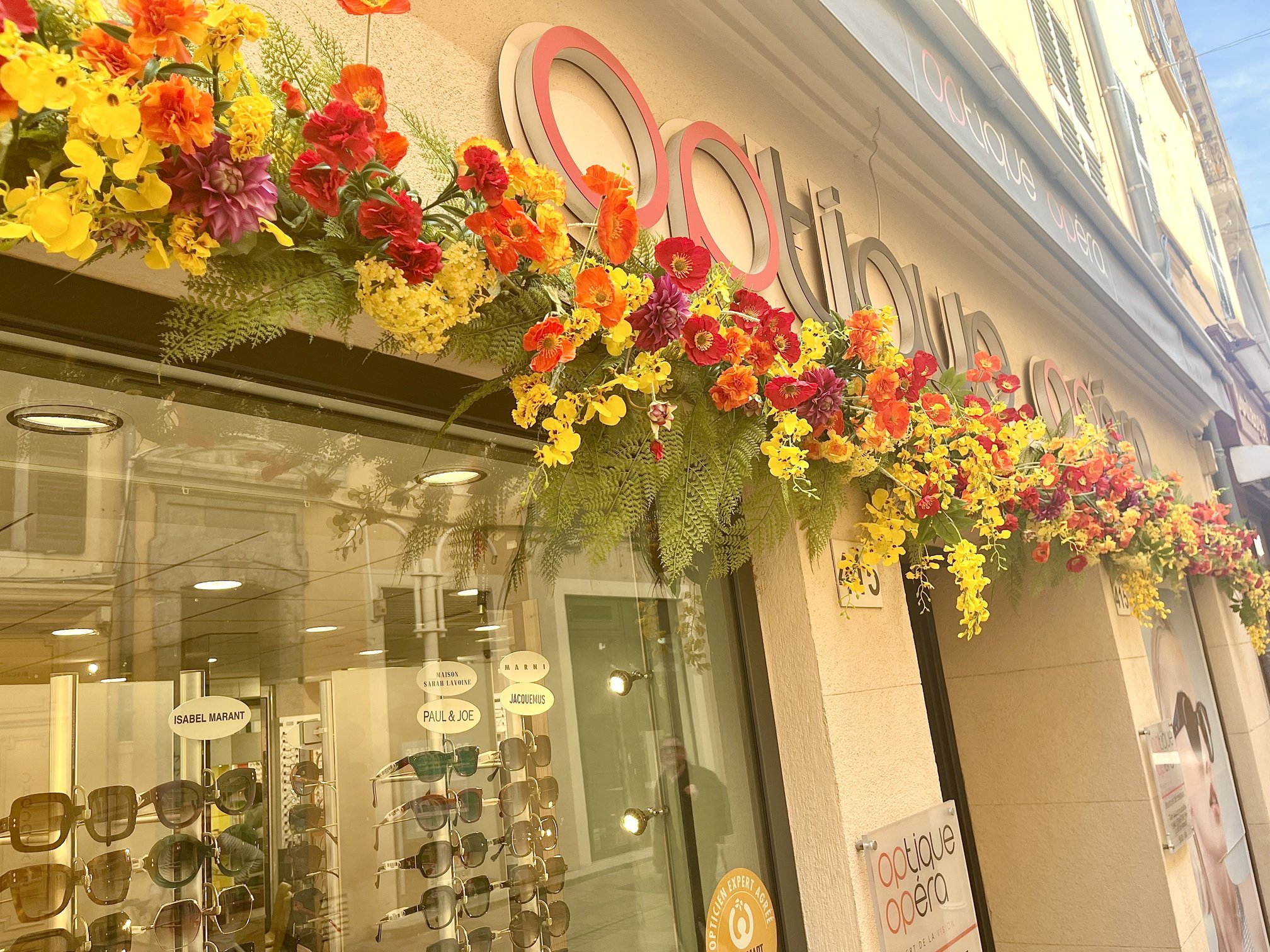 Devanture d'Optique Opéra à Toulon ornée de coquelicots et fleurs artificielles colorées