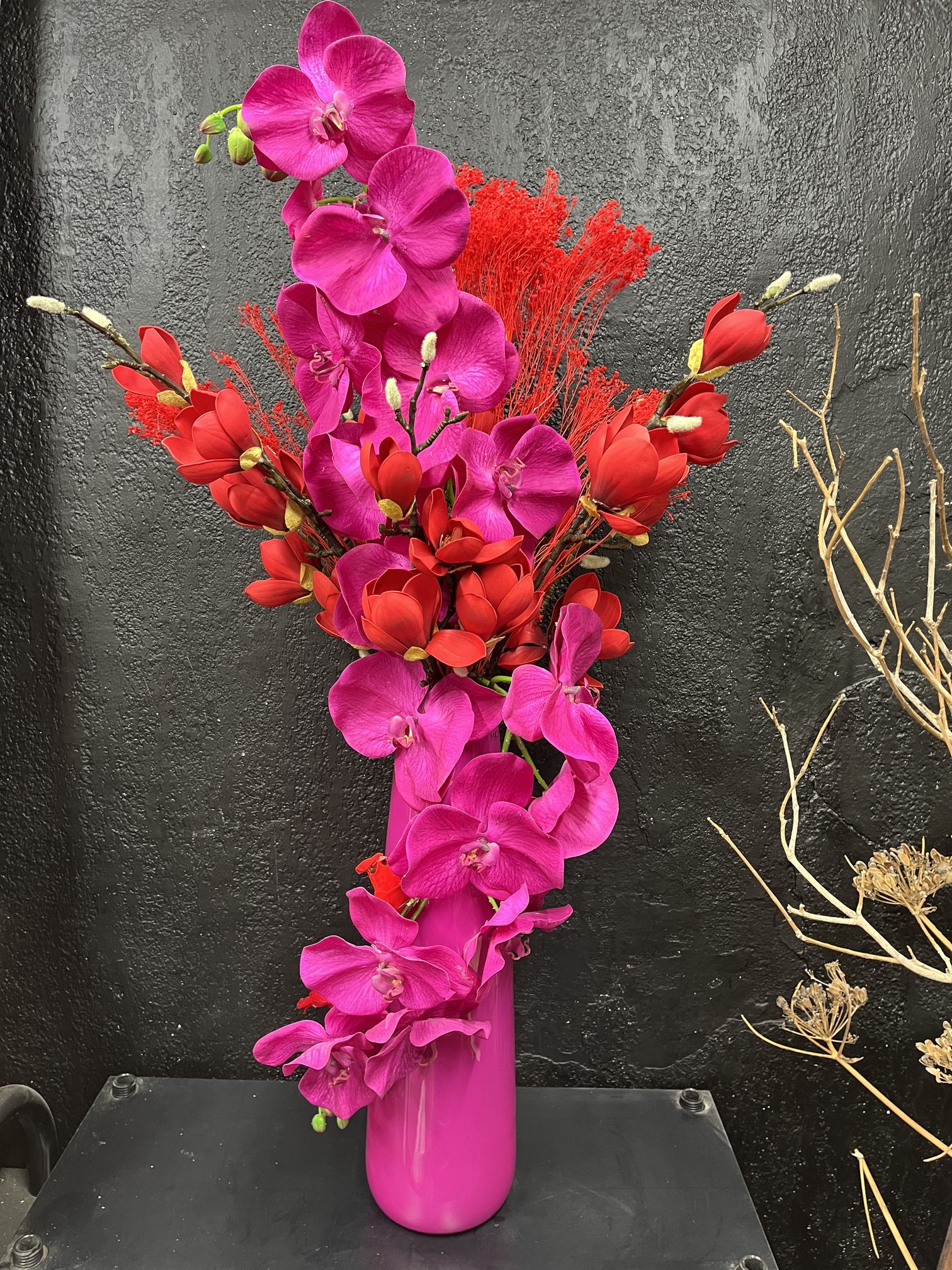 Composition artificielle en orchidées fuchsia et magnolias rouges, disponible en location chez Maluna