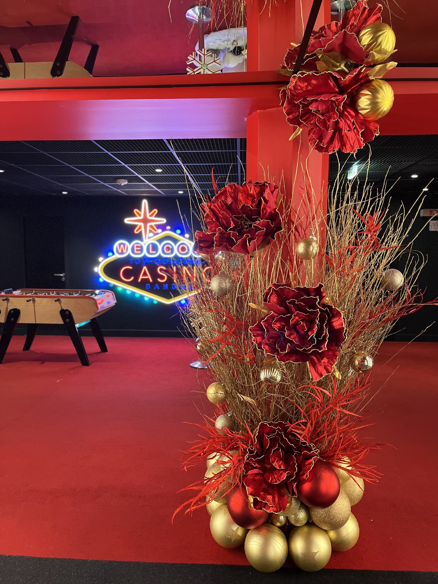 Fleurs rouges et dorées ornant un pilier près de l'enseigne néon du Casino Partouche Bandol pour Noël