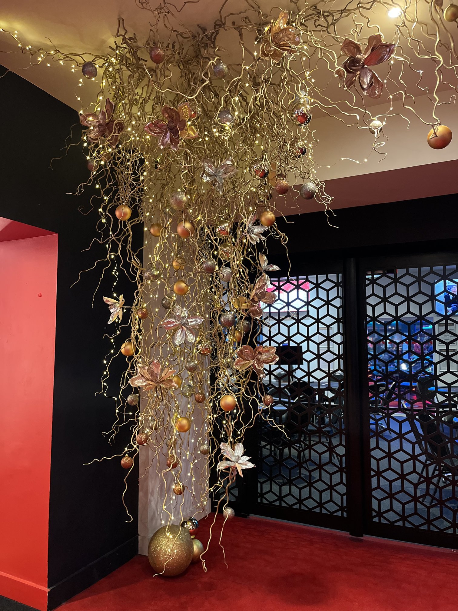 Installation suspendue de branches et fleurs dorées illuminées au plafond du Casino Partouche Bandol