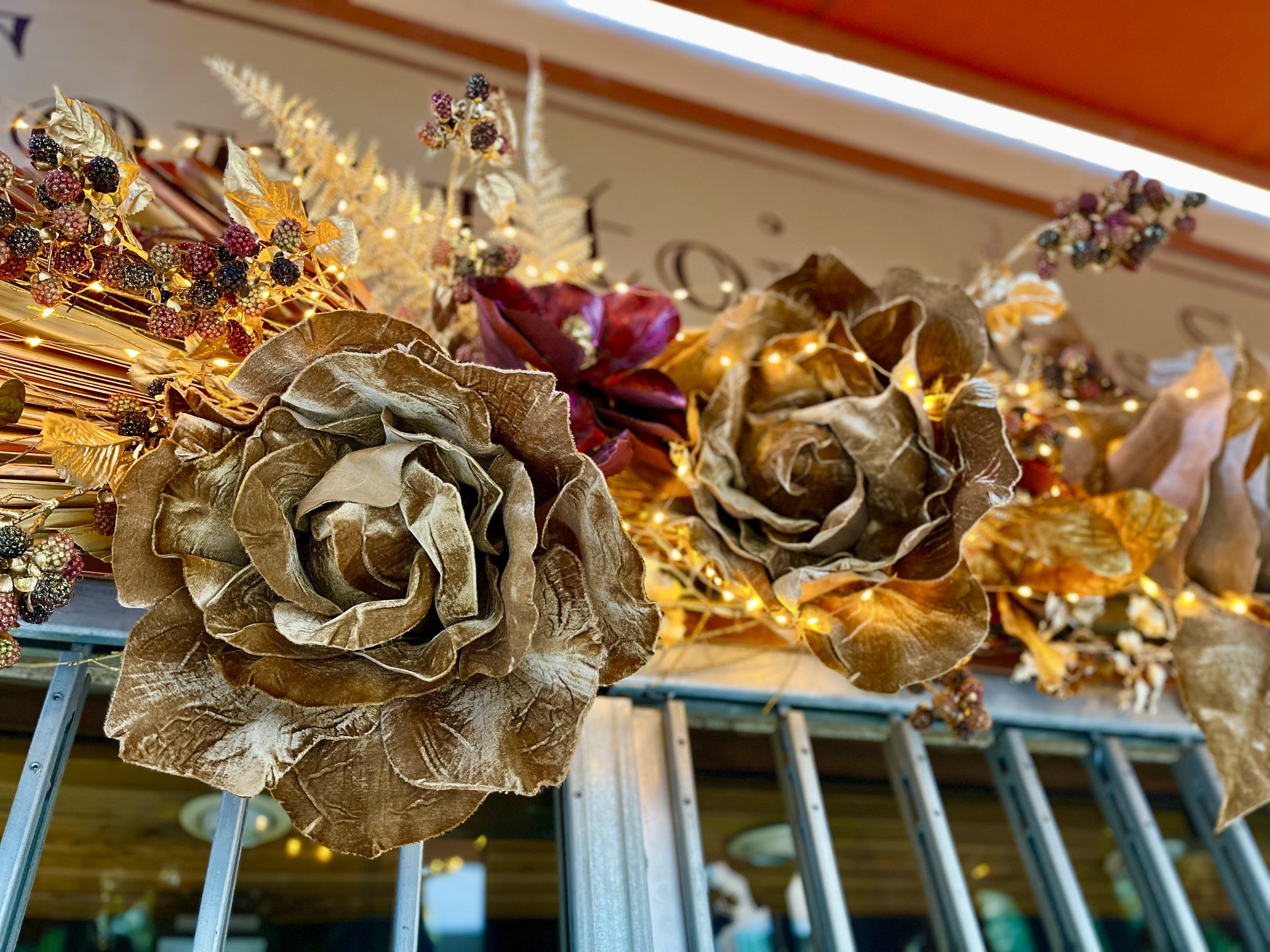 Roses dorées et bordeaux illuminées de guirlandes lumineuses, décoration de Noël d'une devanture à Toulon