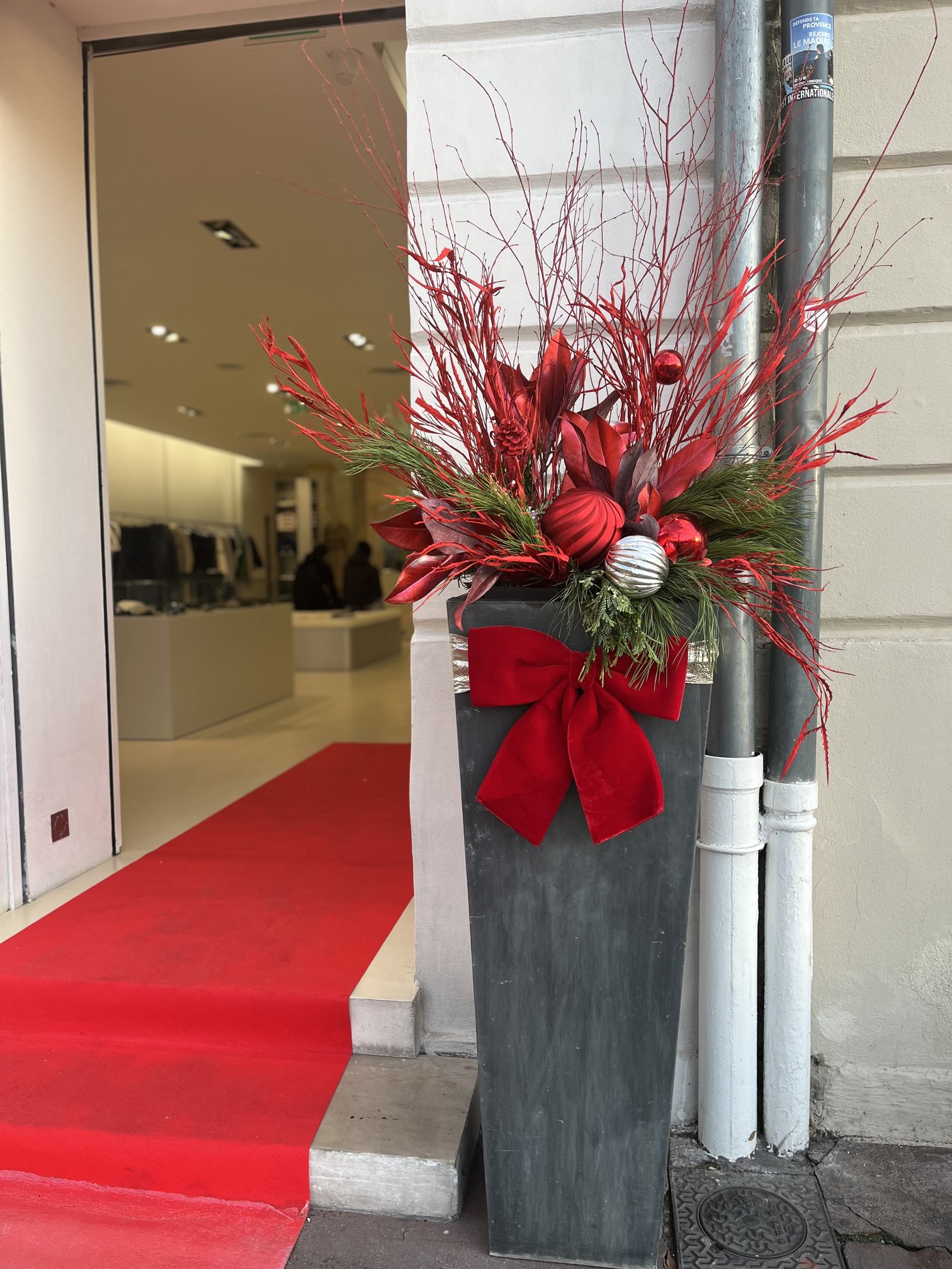 Grand bac fleuri de Noël en branches rouges et boules argentées à l'entrée d'une boutique à Toulon