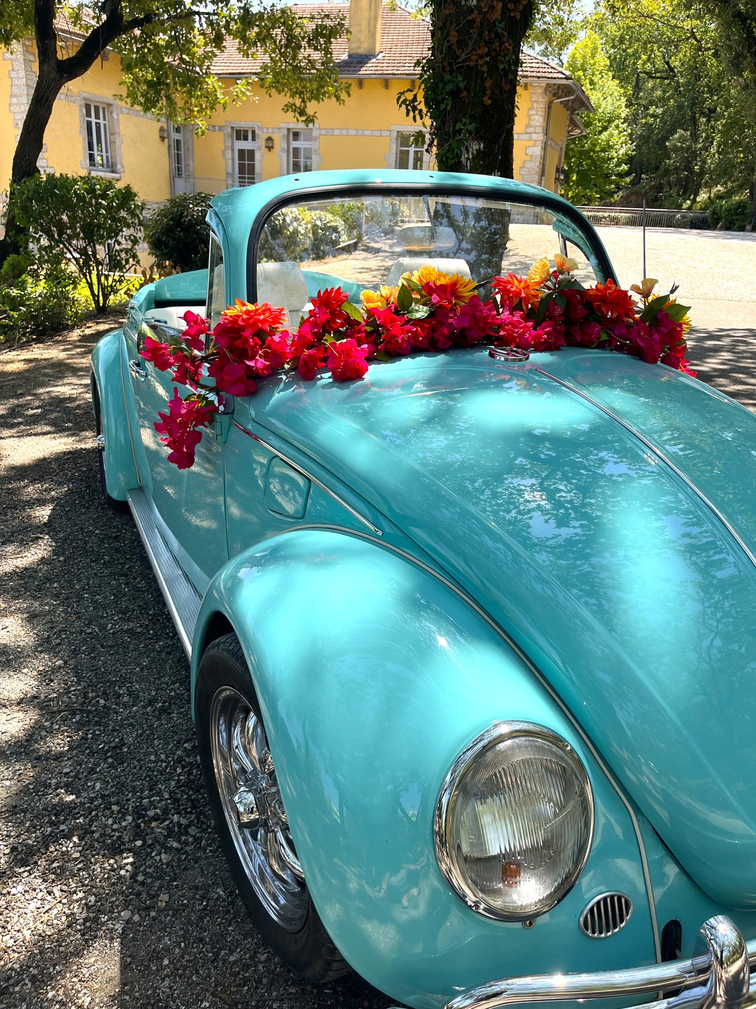 Voiture de mariage décorée d'une guirlande de fleurs artificielles rouges et oranges