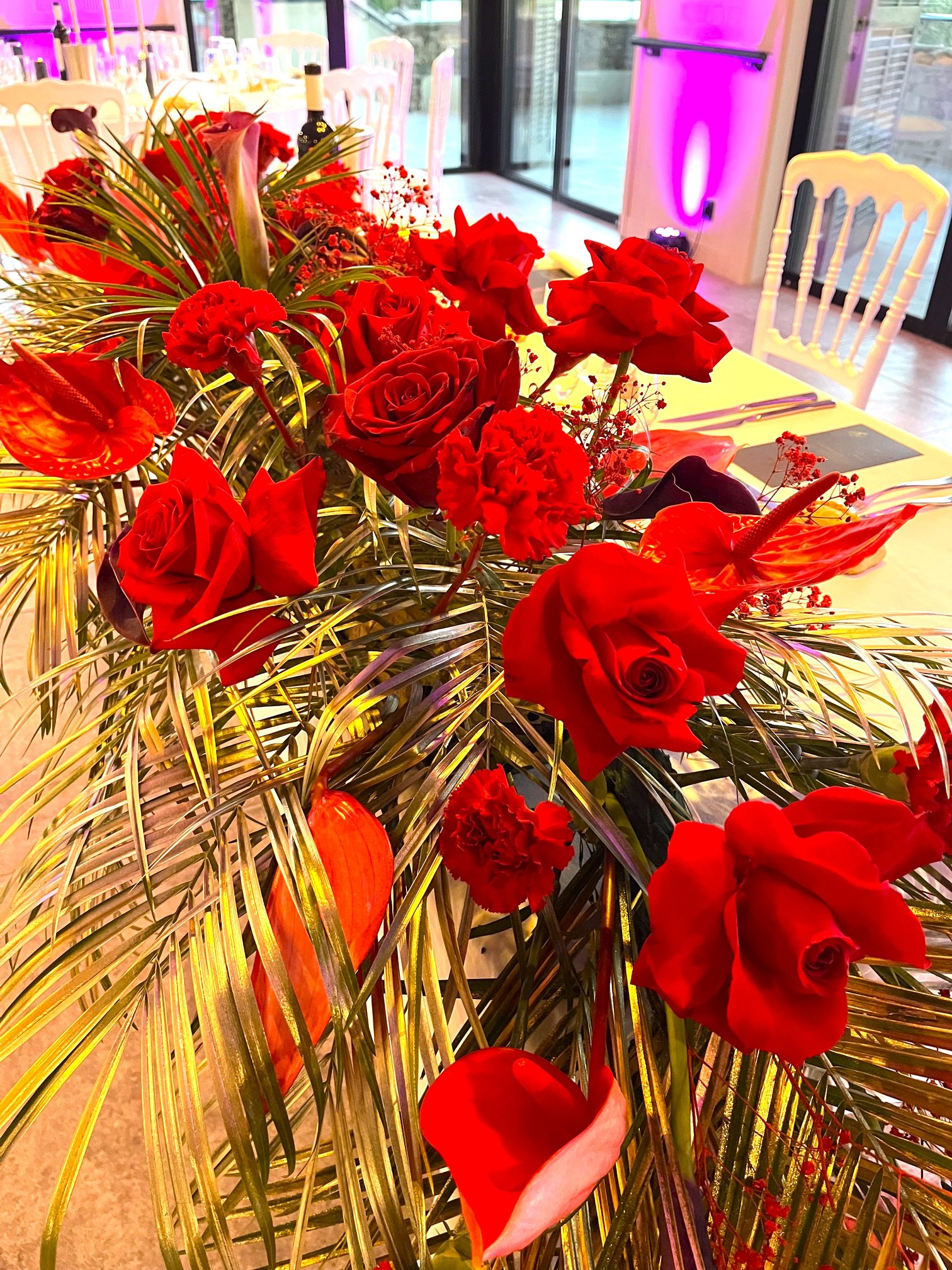 Centre de table en roses rouges et feuillage doré pour un mariage élégant