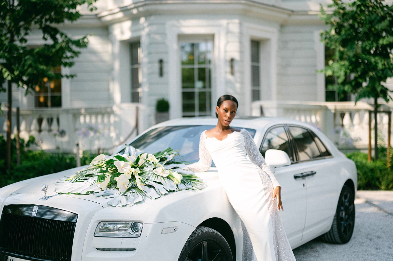 Bouquet de mariée en arums et feuillages tropicaux sur le capot d'une voiture de prestige
